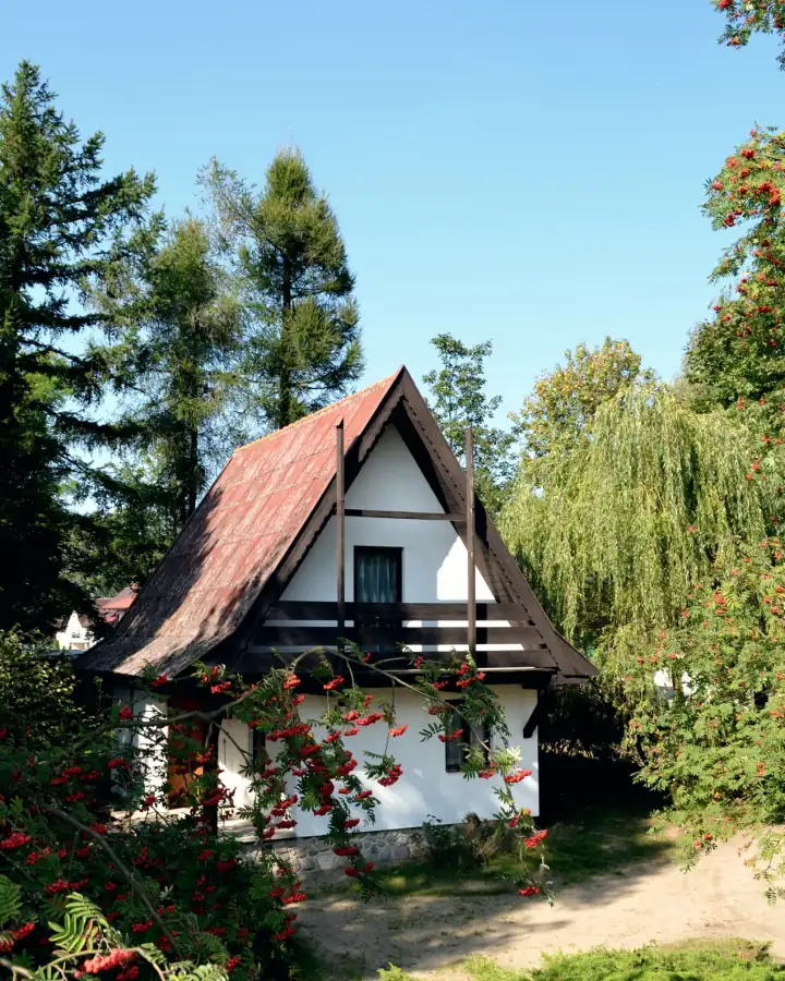 Piętrowy domek z czerwonym dachem wśród jarzębin