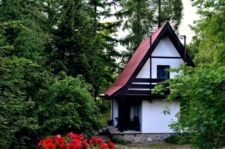 Domek piętrowy frontem, z czerwonymi pelargoniami na pierwszym planie