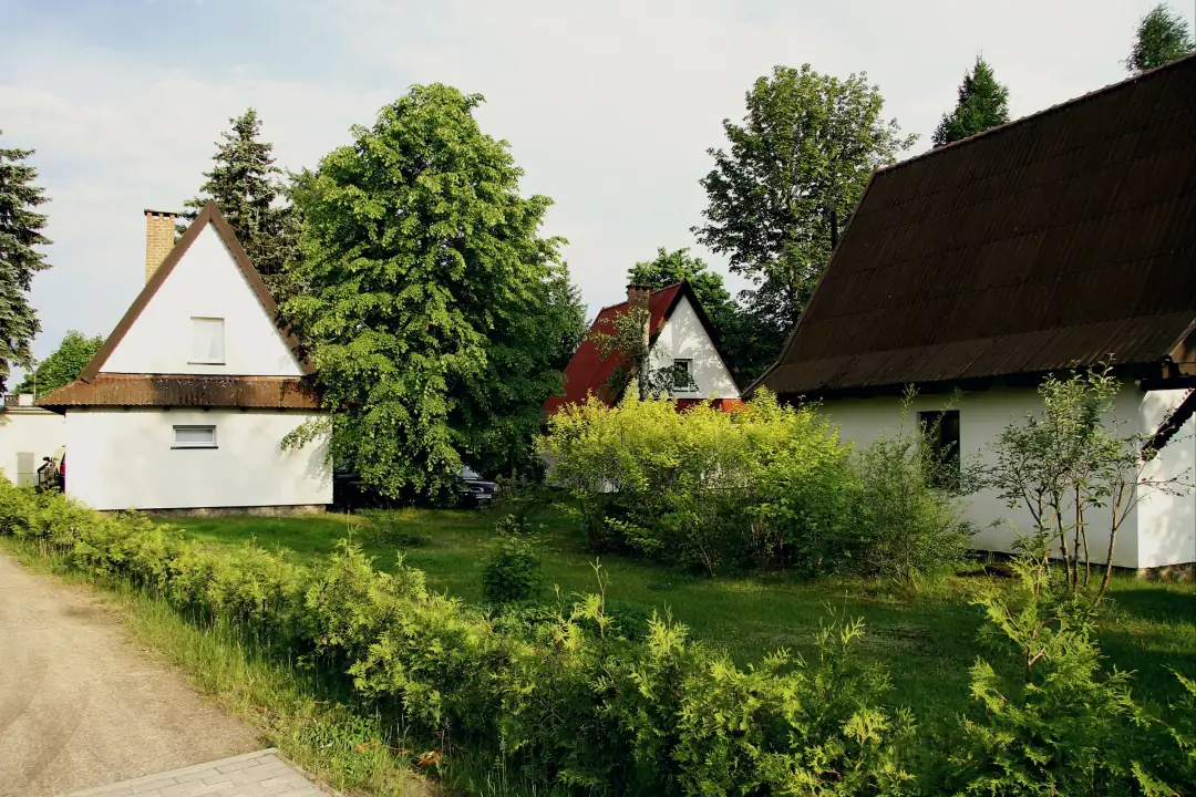 Kilka domków piętrowych wśród zieleni, trawnik i alejka