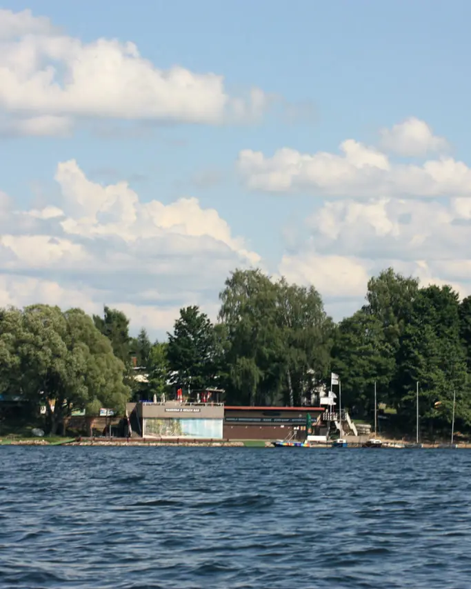 Widok z&nbsp;jeziora na ośrodek i&nbsp;przystań wśród drzew