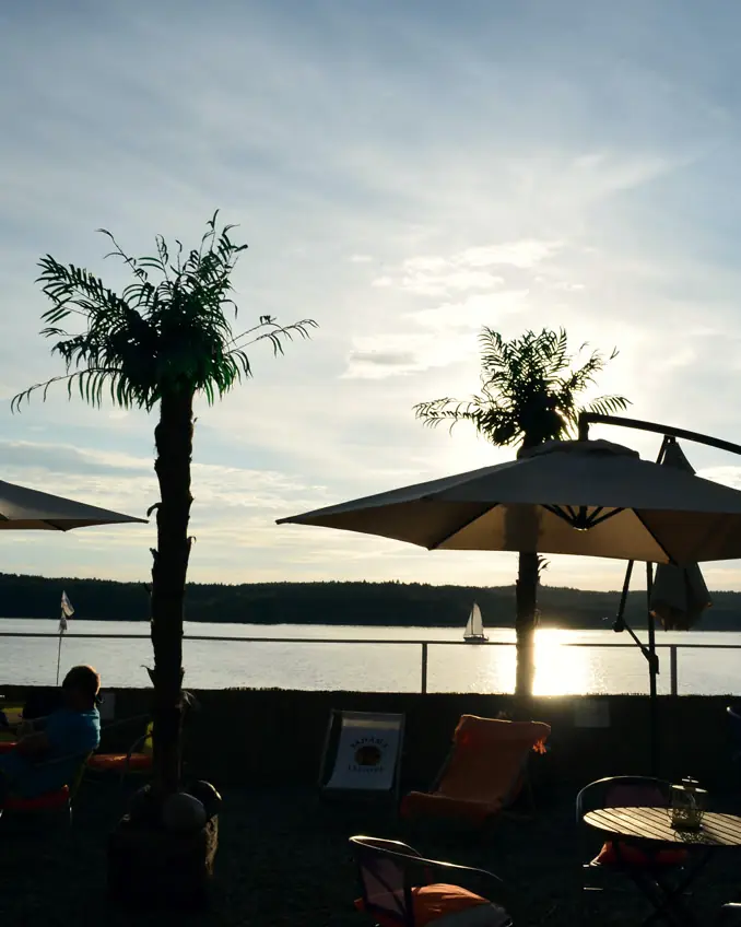 Zachód słońca nad jeziorem, sylwetki palm i parasoli Beach Baru